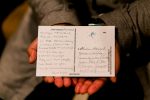 A photo of hands holding a postcard from claud's performance.