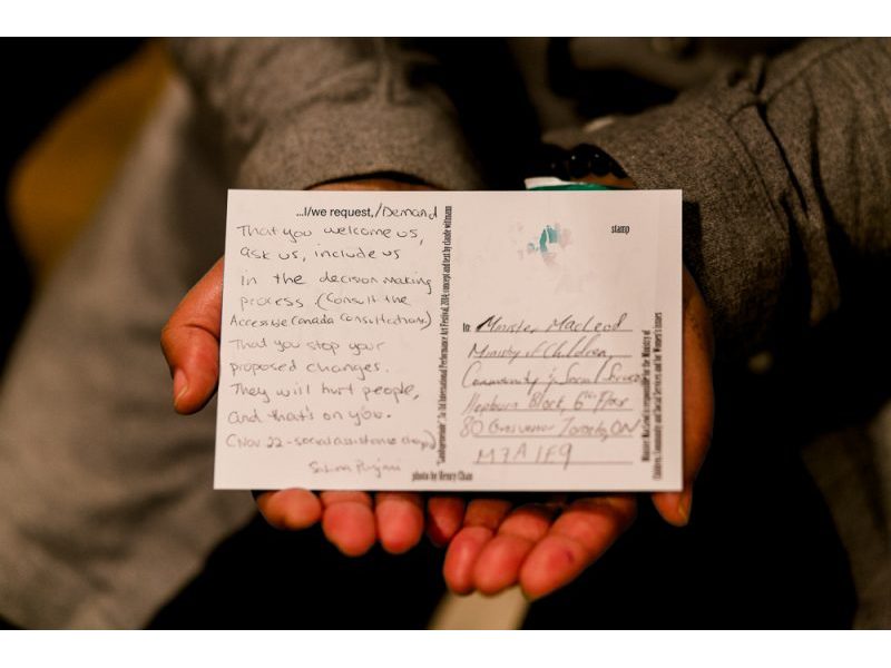 A photo of hands holding a postcard from claud's performance.